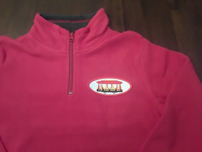 Red fleece Sweater with a Trolley Patch.