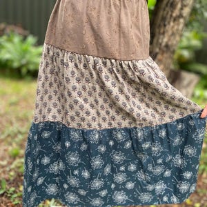 Peut inclure: Une jupe à volants avec une couche supérieure marron, une couche intermédiaire beige à motif floral et une couche inférieure bleu foncé à motif de pissenlits blancs.