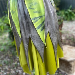 May include: A green and grey skirt with a layered design. The skirt is made of a soft, flowing fabric and has a unique, asymmetrical hemline.
