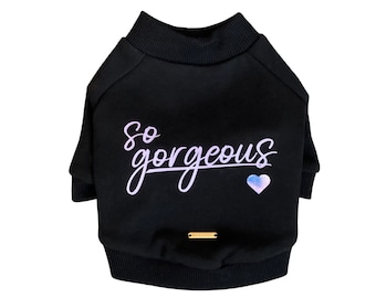 Puede incluir: Suéter negro para perro con el texto "so gorgeous" en morado y un corazón holográfico.