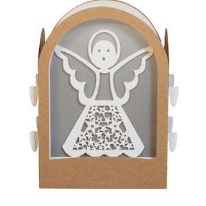 Op de afbeelding: Een papieren engeldecoratie met een witte engel in een bruin boogvormig frame. De engel heeft uitgespreide vleugels en een rok met sterrenpatroon. Kleine witte lipjes zijn aan de zijkanten zichtbaar. De achtergrond is zachtgrijs.