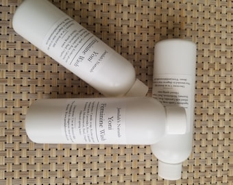 May include: Three white plastic bottles with a label that reads "Jamilah's Naturals Yoni Feminine Wash" and lists ingredients including "Cande Soap, Rose, Calendula, Lavender, Rosemary, Mediterranean Lilac, Organic Flowered Spring Water".