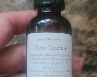 Peut inclure: Une bouteille en verre brun avec un compte-gouttes et une étiquette blanche qui indique "Jamilah's Naturals Thyro Tincture". L'étiquette énumère les ingrédients : Ashwagandha, ortie piquante, éléuthérocoque, ginseng sibérien, cumin noir, glycérine végétale, eau de source. L'étiquette comprend également des instructions d'utilisation : Prendre 10 à 30 gouttes dans une petite quantité de liquide deux fois par jour. Augmenter la dose si nécessaire. Ce produit n'est pas destiné à diagnostiquer, traiter, guérir ou prévenir une maladie.