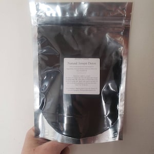 May include: A silver resealable pouch containing a black powder labelled "Natural Armpit Detox" with the ingredients listed as "Activated Bamboo Charcoal, Bentonite Clay, French Pink Clay". The directions are to apply to armpits.