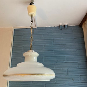 Può includere: Un lampadario da soffitto bianco con un bordo dorato e una catena bianca che pende da un soffitto bianco.