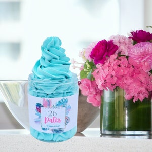 Op de afbeelding: Een blauwe geklopt zeep in een glazen pot met een label dat "Butterfly Bliss 26 Dates Whipped Soap" zegt.