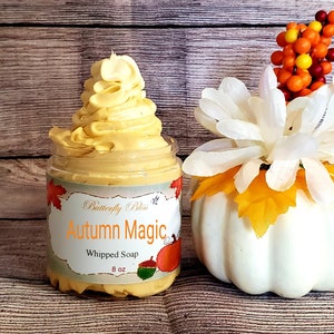 May include: A jar of whipped soap labeled "Butterfly Bliss Autumn Magic Whipped Soap 8 oz" with a fall-themed design. The soap is a light yellow color and is topped with a swirl of whipped cream.