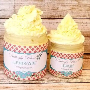 May include: Two jars of whipped soap, both labeled "Butterfly Bliss Lemonade Whipped Soap". The jars are filled with a light yellow whipped soap and have a red and white checkered pattern on the label.