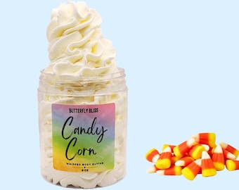 May include: A white whipped body butter in a clear jar with a rainbow label that says "Butterfly Bliss Candy Corn Whipped Body Butter 4 oz".  A pile of yellow, orange, and white candy corn is in the lower right corner of the image.
