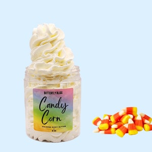 May include: A white whipped body butter in a clear jar with a rainbow label that says "Butterfly Bliss Candy Corn Whipped Body Butter 4 oz".  A pile of yellow, orange, and white candy corn is in the lower right corner of the image.