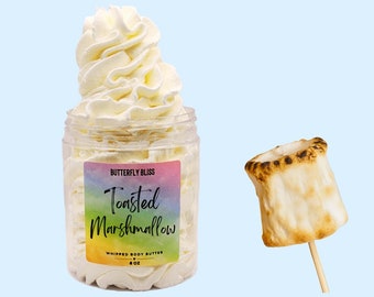 May include: A clear jar filled with a white whipped body butter. The jar has a rainbow label that reads "Butterfly Bliss Toasted Marshmallow Whipped Body Butter 4 oz". A toasted marshmallow is shown on a wooden stick to the right of the jar.