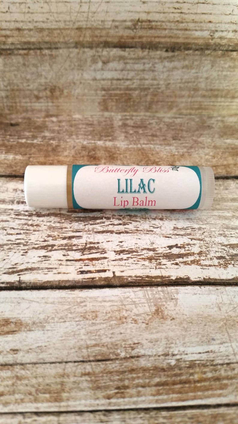 May include: A white tube of lip balm with a teal and gold label that reads "Butterfly Bliss Lilac Lip Balm".