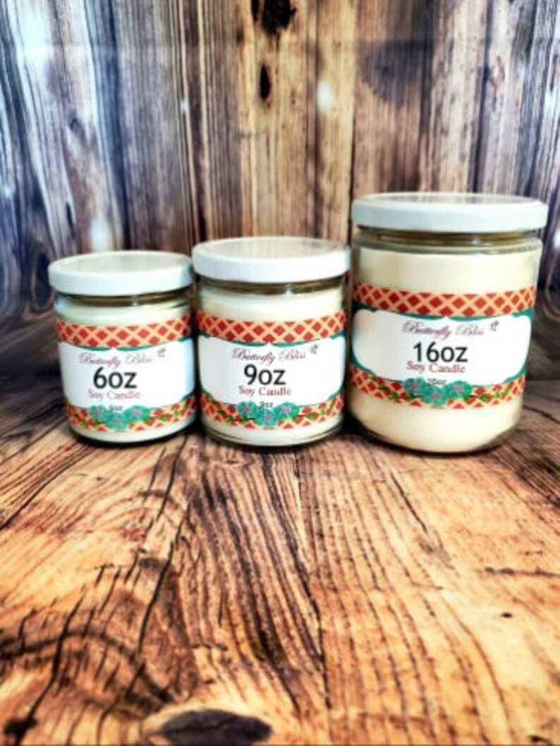May include: Three soy candles in glass jars with white lids. The candles are labeled "6oz", "9oz", and "16oz" and feature a colorful design with the text "Butterfly Bliss".