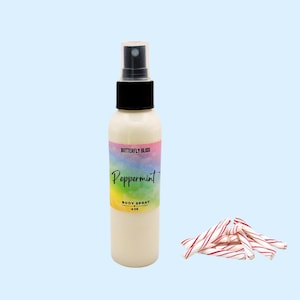 May include: A white body spray bottle with a black cap and a label that reads "Butterfly Bliss Peppermint BODY SPRAY 4 OZ." Next to the bottle are several red and white peppermint candy sticks. The background is a light blue.