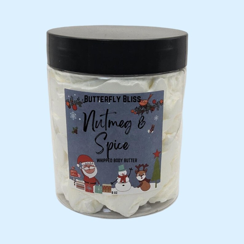 May include: A white 8 oz jar of whipped body butter with a festive label that says "Butterfly Bliss Nutmeg & Spice Whipped Body Butter". The label features a snowman, a reindeer, and Santa Claus.