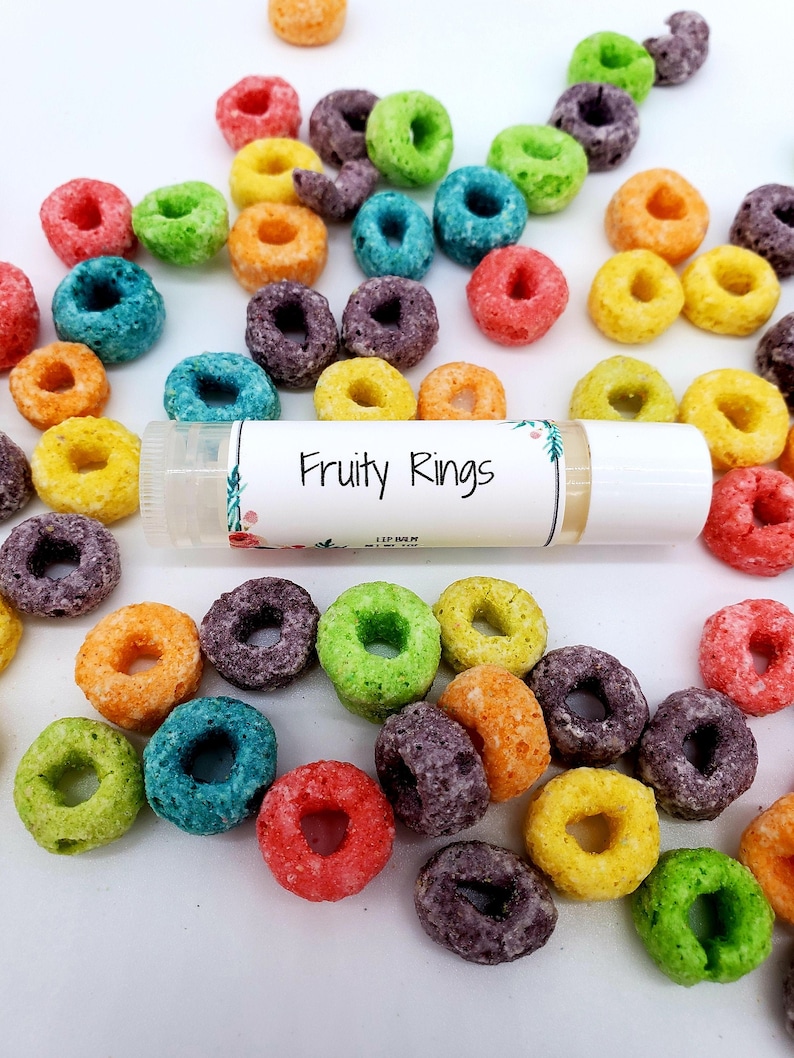 Peut inclure: Un tube de baume &agrave; l&egrave;vres blanc avec les mots "Fruity Rings" imprim&eacute;s sur l'&eacute;tiquette. Le baume &agrave; l&egrave;vres est entour&eacute; d'anneaux de c&eacute;r&eacute;ales color&eacute;s.