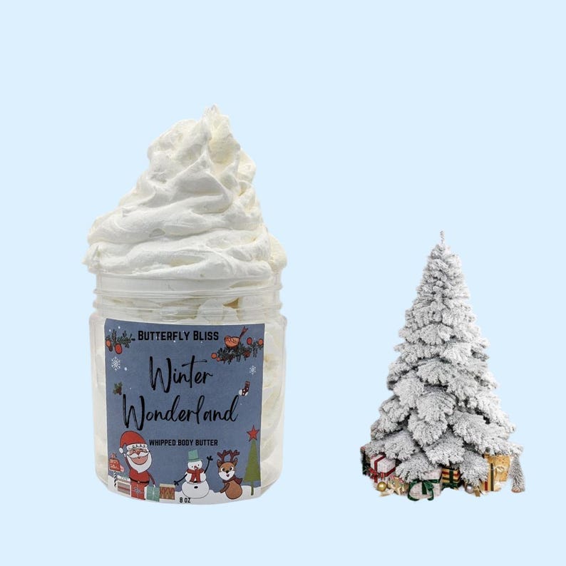 May include: A white jar of whipped body butter with a festive label that reads "Butterfly Bliss Winter Wonderland Whipped Body Butter 8 oz". The label features a cartoon Santa Claus, snowman, and reindeer. A small white Christmas tree with red and gold ornaments is in the background.