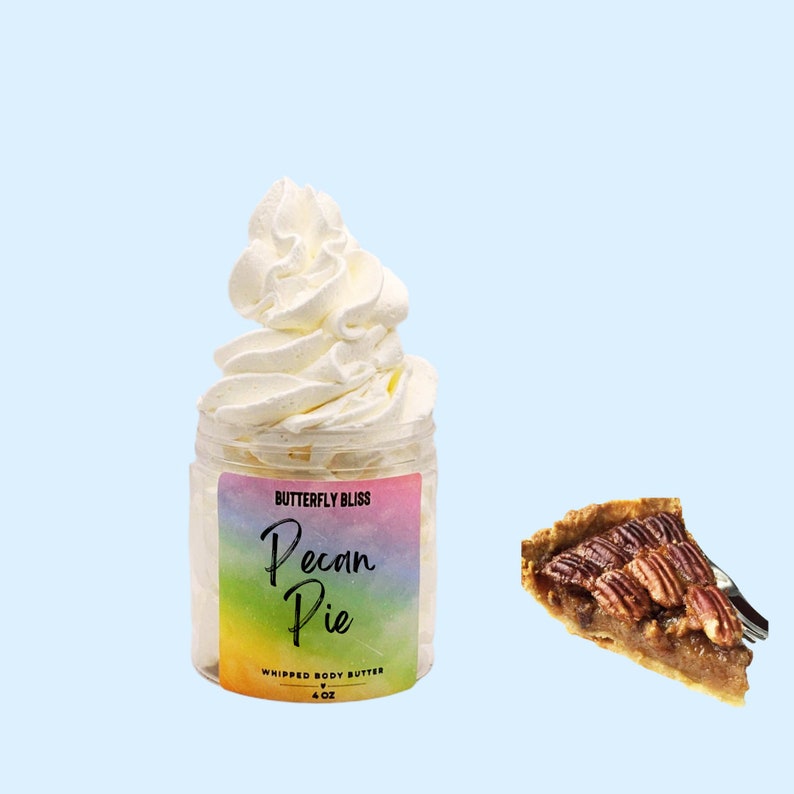 May include: A jar of whipped body butter with a rainbow label that says "Butterfly Bliss Pecan Pie Whipped Body Butter 4 oz". The jar is topped with a swirl of white whipped cream. A slice of pecan pie is shown in the background.