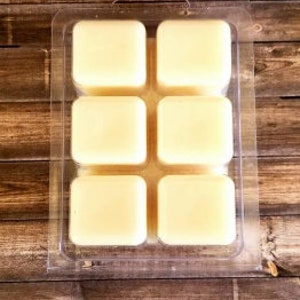 May include: A clear plastic tray with six individual wax melts. The wax melts are a pale yellow color and are arranged in a 2x3 grid.