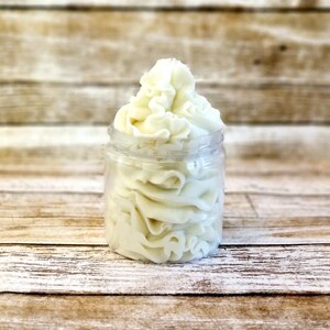 K&ouml;nnte beinhalten: Ein klares Glasgef&auml;&szlig; gef&uuml;llt mit wei&szlig;er, geschlagenem K&ouml;rperbutter. Die Butter ist hoch im Gef&auml;&szlig; gestapelt und hat eine glatte, cremige Textur.
