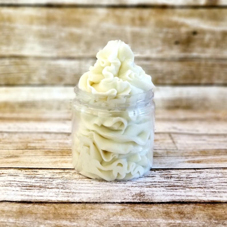 K&ouml;nnte beinhalten: Ein klares Glasgef&auml;&szlig; gef&uuml;llt mit wei&szlig;er, geschlagenem K&ouml;rperbutter. Die Butter ist hoch im Gef&auml;&szlig; gestapelt und hat eine glatte, cremige Textur.
