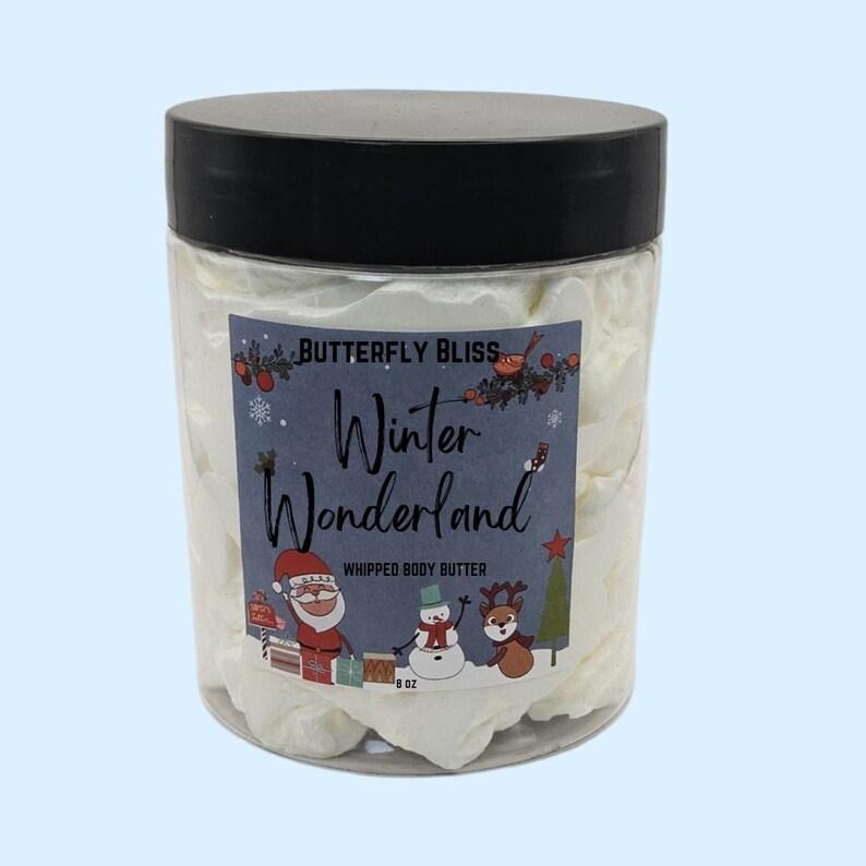 May include: A white whipped body butter in a clear jar with a black lid. The jar has a label that says "Butterfly Bliss Winter Wonderland Whipped Body Butter 8 oz.". The label features a cartoon Santa Claus, snowman, and reindeer.