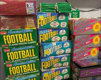 May include: A collection of vintage football card boxes, including Fleer '91, 1990 Premiere Edition, and 1991 NFL Pro Football Plus. The boxes are in various colors, such as green, blue, red, and pink, and feature football-related graphics and text.