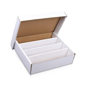 Puede incluir: Una caja de almacenamiento de cartón blanco con una tapa abatible adjunta, que cuenta con tres divisores internos que crean cuatro compartimentos separados. El exterior es blanco, mientras que las superficies interiores de la caja y los divisores son de color marrón.