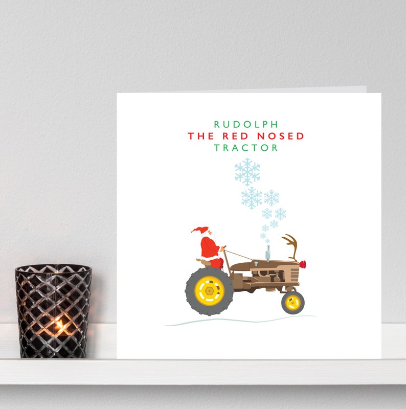 May include: A Christmas card with the text "Rudolph the Red Nosed Tractor". It depicts Santa Claus driving a brown tractor with reindeer antlers and snowflakes. A lit candle in a black glass holder is on the left.