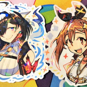 May include: Two anime-style stickers featuring female characters. One has black hair and a blue and white outfit, the other has brown hair and a white and yellow outfit. Both stickers have a holographic effect and are surrounded by a white border.