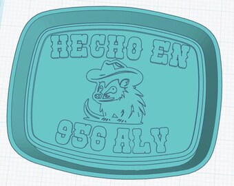 May include: A turquoise-coloured, rectangular tray with rounded corners. The tray features the text "HECHO EN 956 ALY" in bold, stylized letters. A cartoon hedgehog wearing a cowboy hat is in the centre.