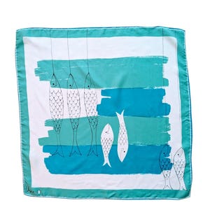 Peut inclure: Foulard carré en soie sur le thème marin. Le foulard présente un fond blanc avec des coups de pinceau turquoise et bleu. Des dessins au trait noirs de poissons sont suspendus à des lignes et regroupés en bas. Le foulard a une bordure turquoise.