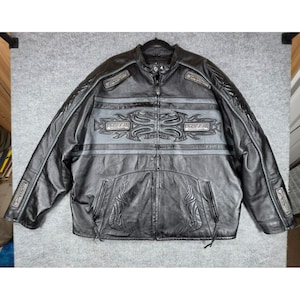 May include: A black leather motorcycle jacket featuring a gray horizontal chest panel with embossed tribal patterns and the word SPEED printed twice. The jacket includes a full-length front zipper, a mandarin collar, and zippered pockets.