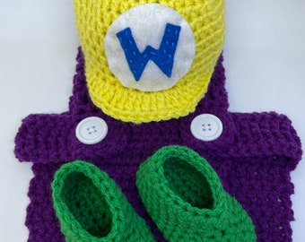May include: A handmade crochet baby outfit in a Wario theme. The set includes a yellow hat with a white and blue "W" emblem, a purple jumpsuit with white buttons, and green crochet shoes. The outfit is designed for infants.
