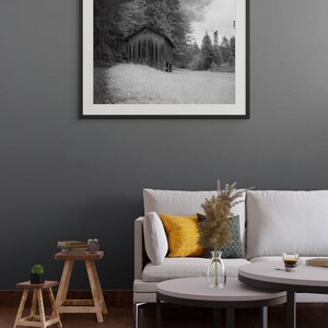 Black and white photograph of a mountain cabin on Mount Pilatus in the Swiss Alps, shown as a framed print hanging in a furnished room