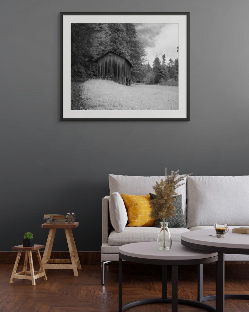 Black and white photograph of a mountain cabin on Mount Pilatus in the Swiss Alps, shown as a framed print hanging in a furnished room