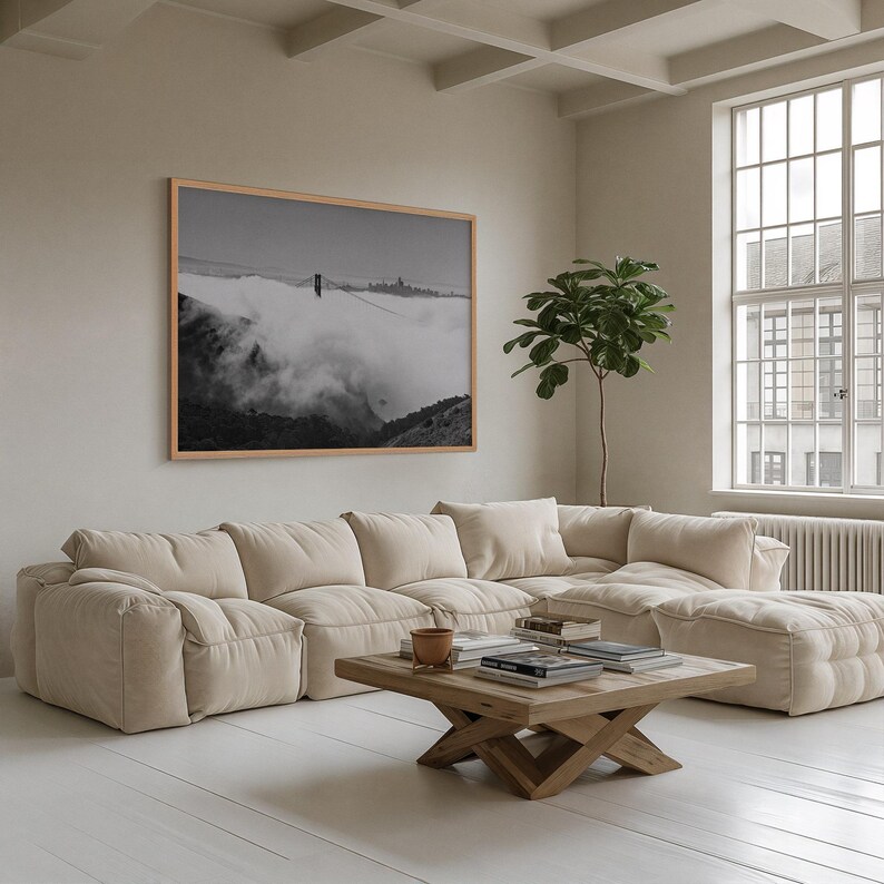 Black and white photograph of the Golden Gate Bridge sinking into fog, shot on 4x5 film, shown as a framed print on a gallery wall