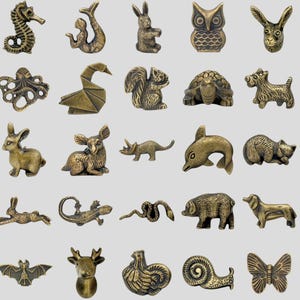 Puede incluir: Una colección de pequeñas figuras de animales de color bronce. El surtido incluye un caballito de mar, una sirena, un conejo, un búho y otras criaturas. Estas piezas decorativas son ideales para coleccionistas o para añadir un toque único a la decoración del hogar.