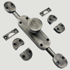 May include: A dark silver-toned metal window sash lock featuring a central knob on an elongated base plate, two sliding bolt ends, two rectangular strike plates, and four semi-circular mounting brackets, all with pre-drilled screw holes.