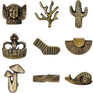 May include: A collection of antique brass-colored decorative knobs and pulls in various shapes. Designs include a shirt, angel, branch, cactus, anchor, flower, crown, sock, sunburst, padlock, mushroom, snail, butterfly, and more.