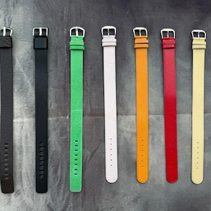Può includere: Sette cinturini colorati per orologi: nero, verde, bianco, arancione, rosso e giallo. Ogni cinturino ha una fibbia argentata e una serie di fori per la regolazione. I cinturini sono realizzati in un materiale strutturato.