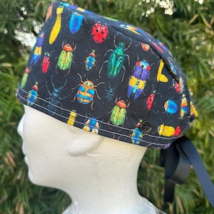 May include: A black scrub hat with a colorful bug pattern. The hat has a tie on the back.
