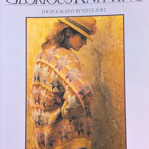 May include: The cover of a knitting book, "GLORIOUS KNITTING" by Kaffe Fassett, with a photograph by Steve Lovi. The image shows a person wearing a patterned knitted sweater and a straw hat. The text "OVER 30 EXCLUSIVE PATTERNS" is also visible.