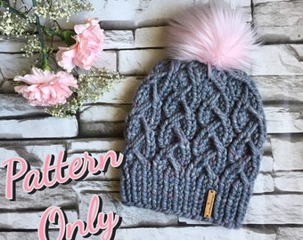 May include: A grey knitted hat with a pink faux fur pom pom. The hat has a cable knit pattern and a small brown leather tag with the word "Handmade" on it. The text "Pattern Only" is written in pink letters on a grey background.