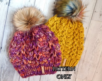 May include: Two chunky knit hats with faux fur pom poms. One hat is a deep purple and orange color, the other is a bright yellow. The hats have a "PATTERN ONLY" label.