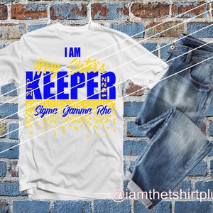 May include: White t-shirt with blue and yellow text that reads "I am My Sister's Keeper 1922 Sigma Gamma Rho". The text is surrounded by yellow confetti.