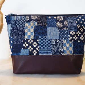 Peut inclure: Une pochette zippée en tissu patchwork bleu et blanc avec un fond en cuir marron.