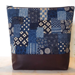 Peut inclure: Une pochette zippée en tissu patchwork bleu et blanc avec un fond en cuir marron.