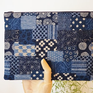 May include: A blue and white patchwork fabric zippered pouch with a variety of traditional Japanese patterns.