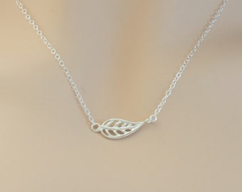 May include: A delicate silver necklace with a leaf pendant. The leaf is cut out and has a delicate design.